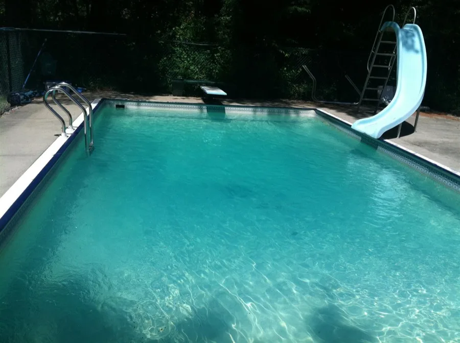 In-ground pool with slide and clear turquoise water